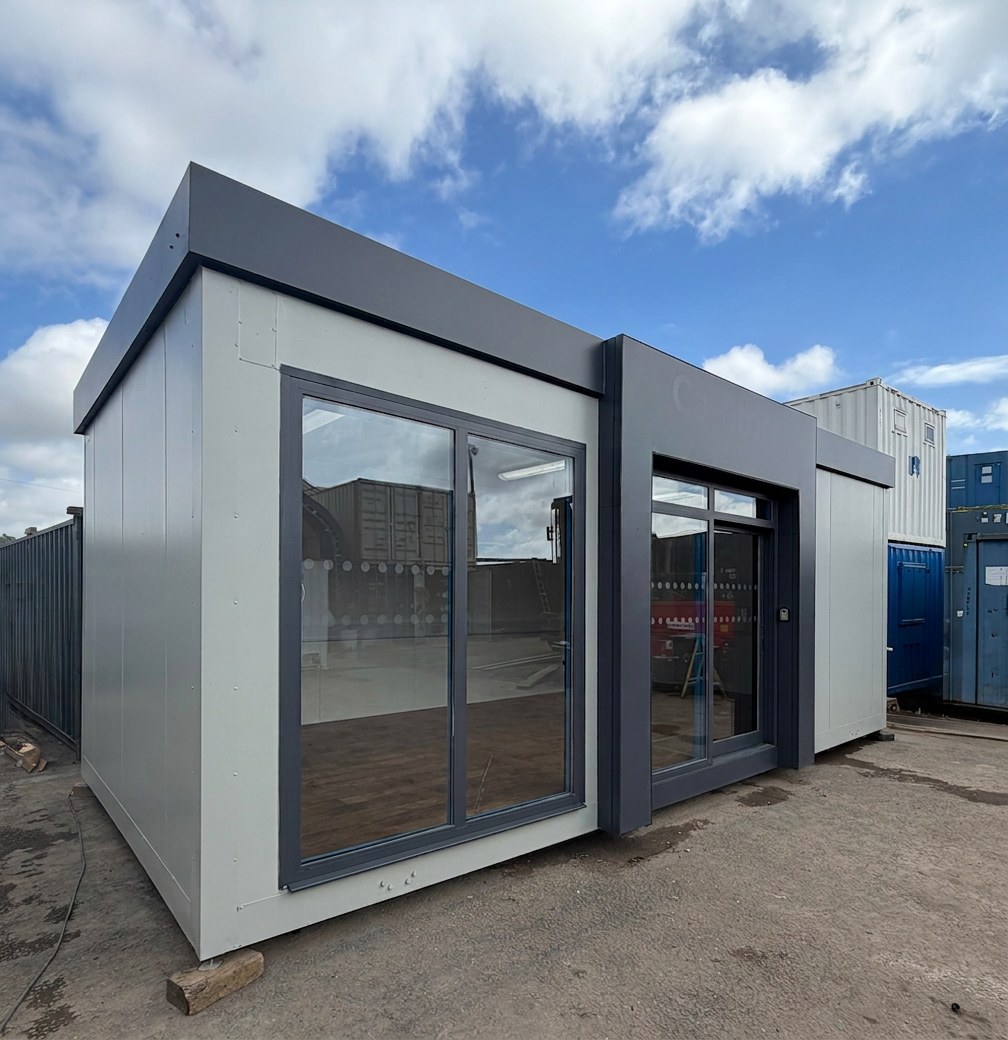 Modern 26x12ft marketing suite featuring large glass windows and grey exterior panels under a blue sky
