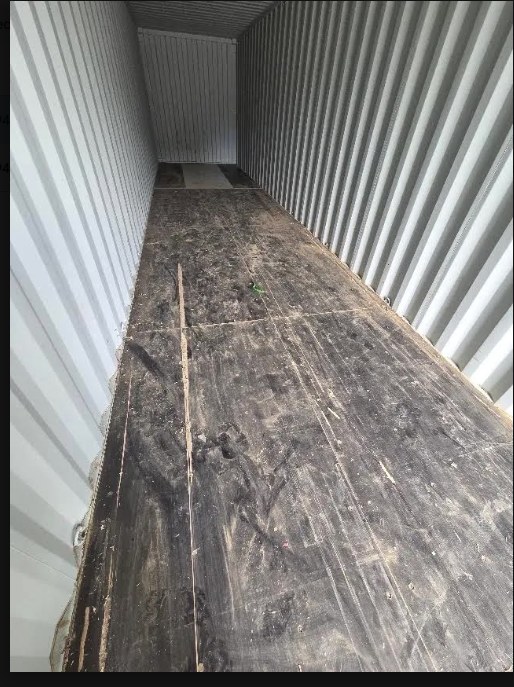 Used 40ft Cargo Container Double Doors — Interior view from the door end showing the worn plywood floor, corrugated steel walls and full container length Used 40ft double-door cargo container — Interior view from the door end showing the worn plywood floor, corrugated steel walls and full container length