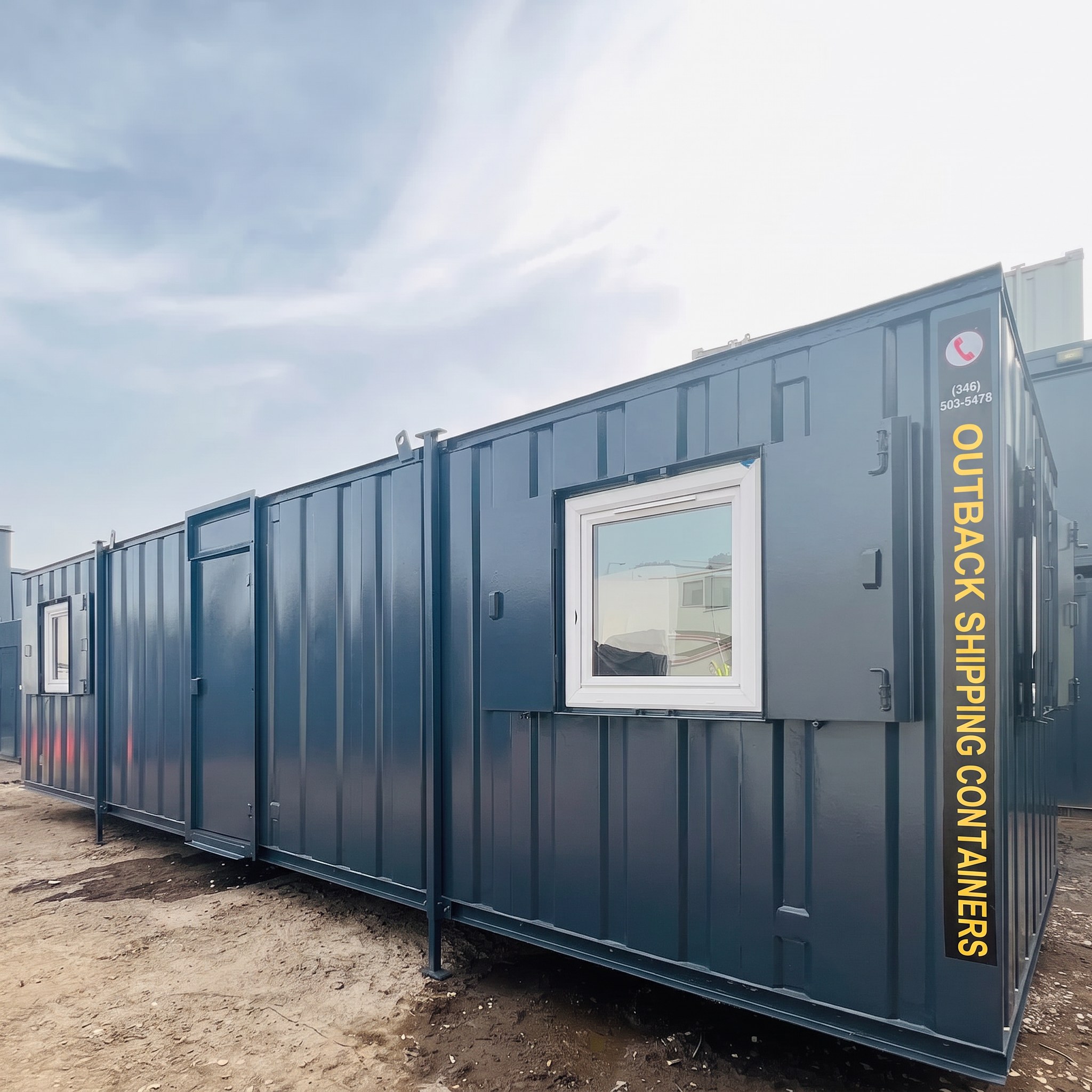 Blue 24x8 ft open plan mobile office cabin with white windows and anti-vandal shutters on a gravel site