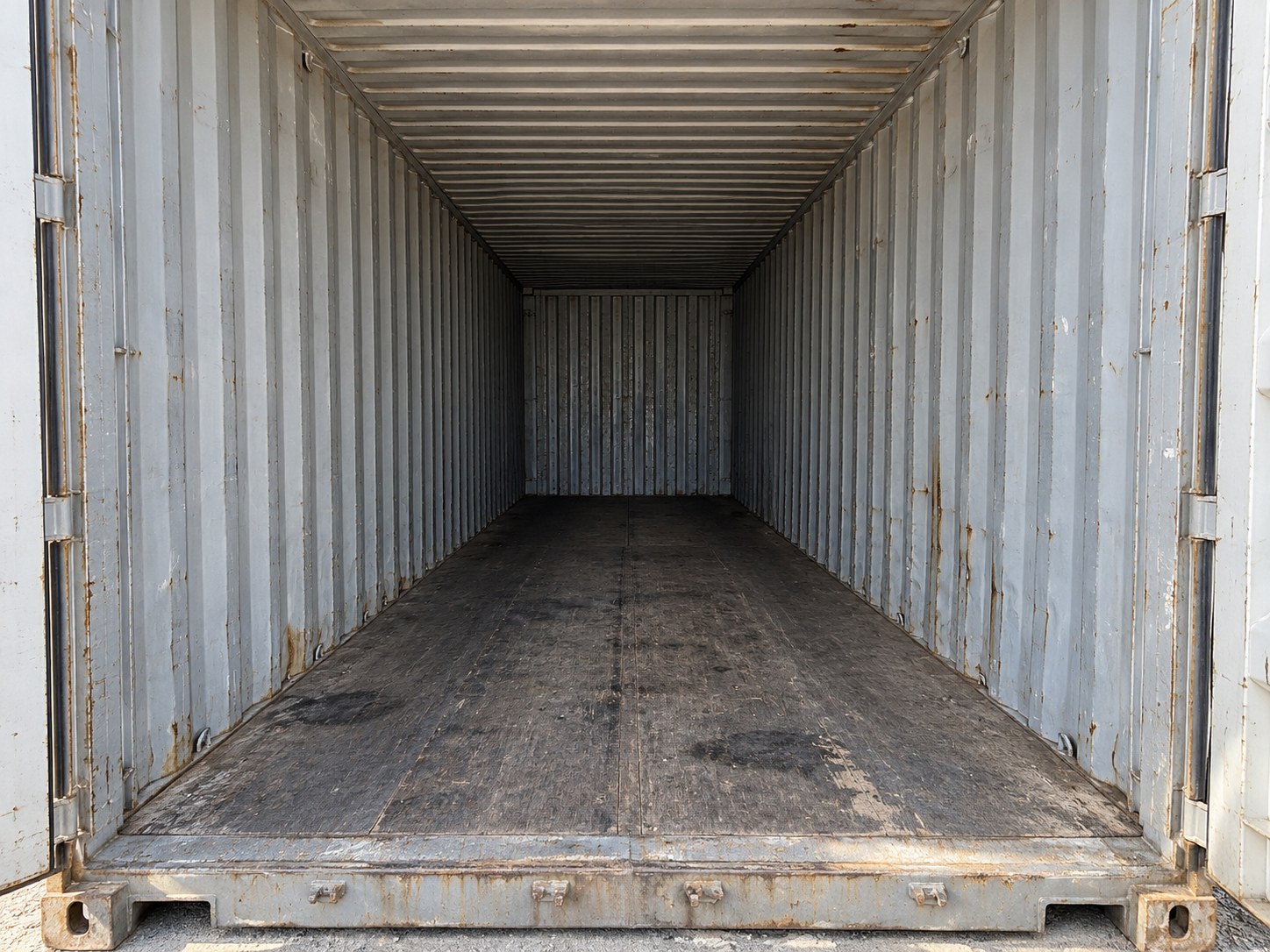 Used 40ft Cargo Container Double Doors — Straight-on view through the open doors showing the empty interior, worn floor and corrugated steel walls Used 40ft double-door cargo container — Straight-on view through the open doors showing the empty interior, worn floor and corrugated steel walls