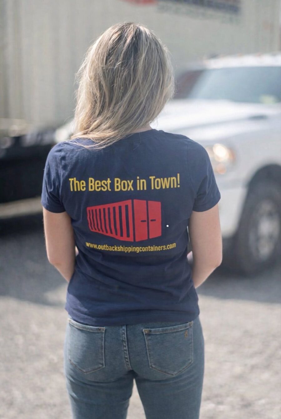 Outback Shipping Containers team member wearing branded "The Best Box in Town!" t-shirt at a container yard